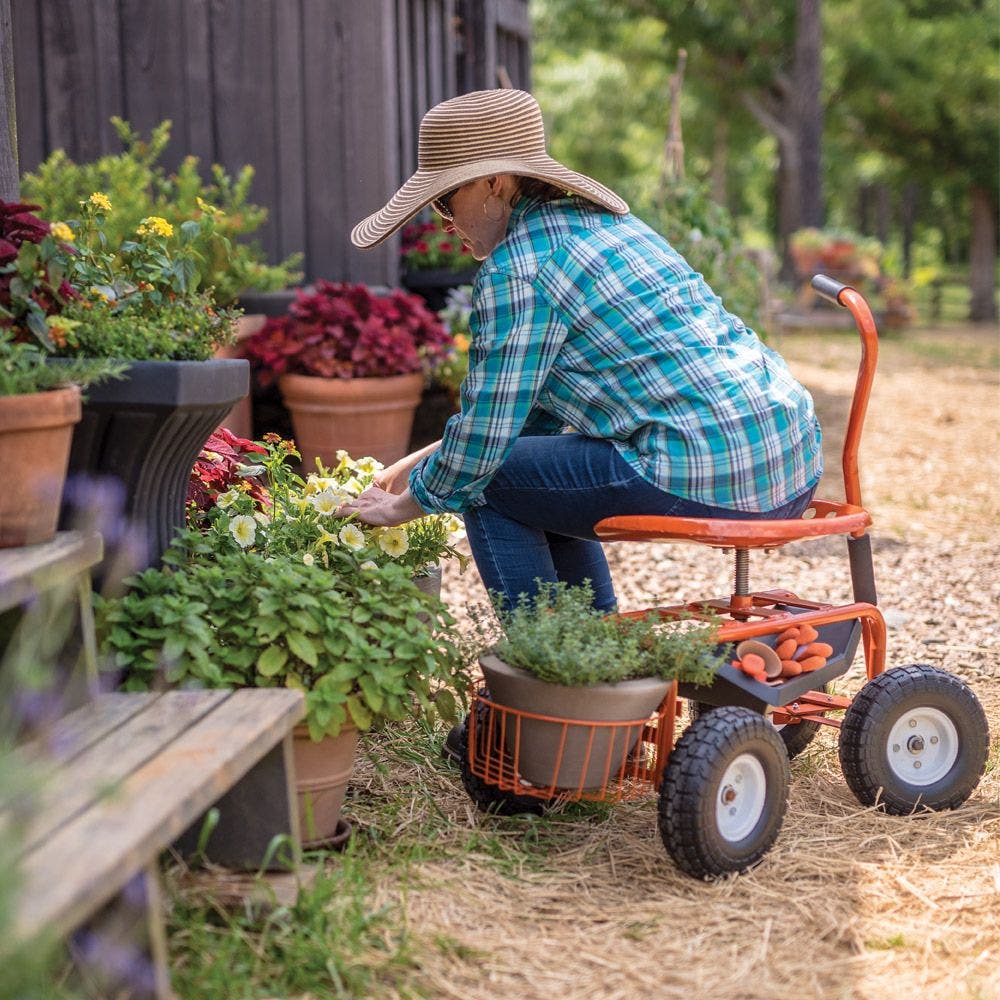 Farmer sitting on knee scooter leaning over potted plants